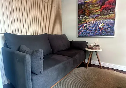 Sofá e pintura vibrante em um dos ambientes de estar do terceiro consultório