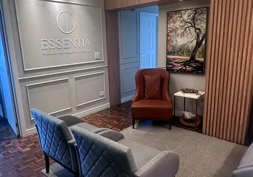 Recepção da clínica Essentia, com a marca em destaque na parede e poltronas para espera
